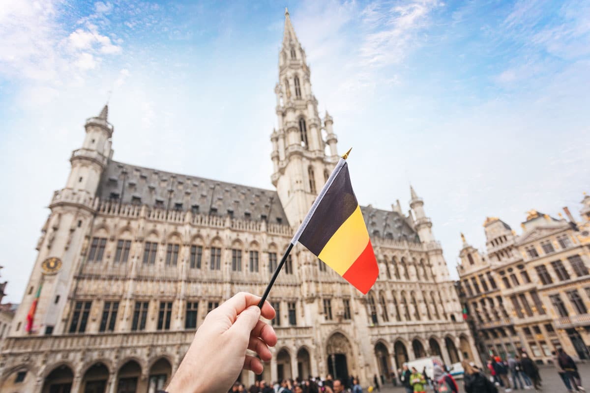 Monument de Belgique ainsi qu'une main qui tient le drapeau Belge