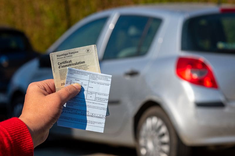personne qui tient le certificat d'immatriculation de sa voiture