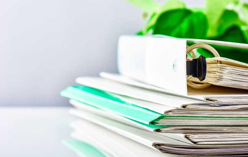 pile de documents et de classeurs posés sur un bureau
