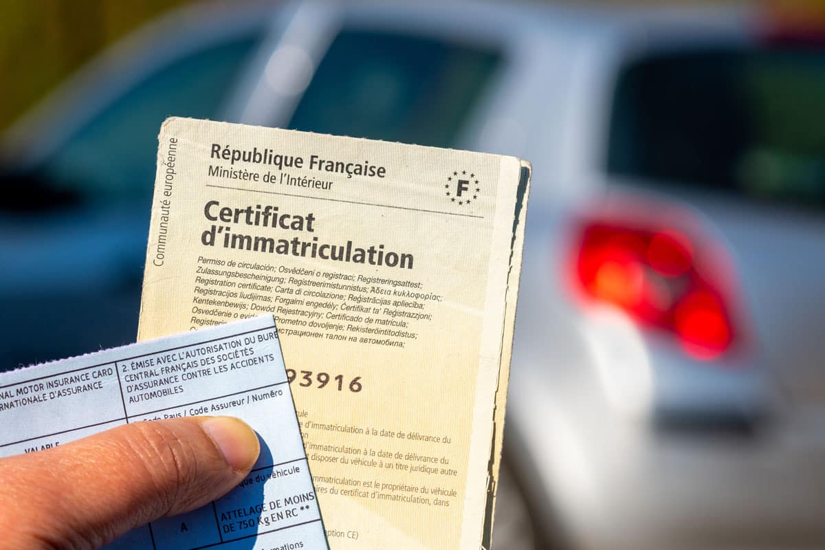Zoom sur une main qui tient un certificat d'immatriculation